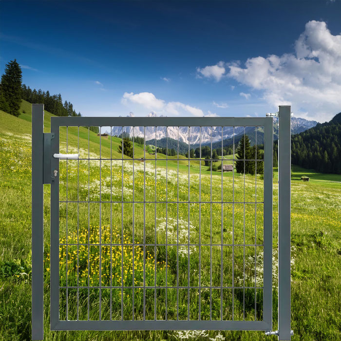 Doppelstabmattenzaun mit Tor auf einer Wiese mit Bergen im Hintergrund